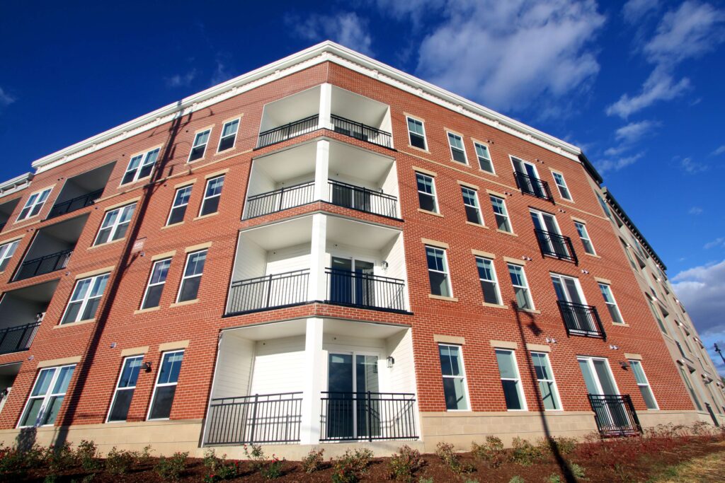 Exterior view of a multi-story red brick apartment building after a building restoration Indianapolis project, featuring clean masonry and white balcony accents.