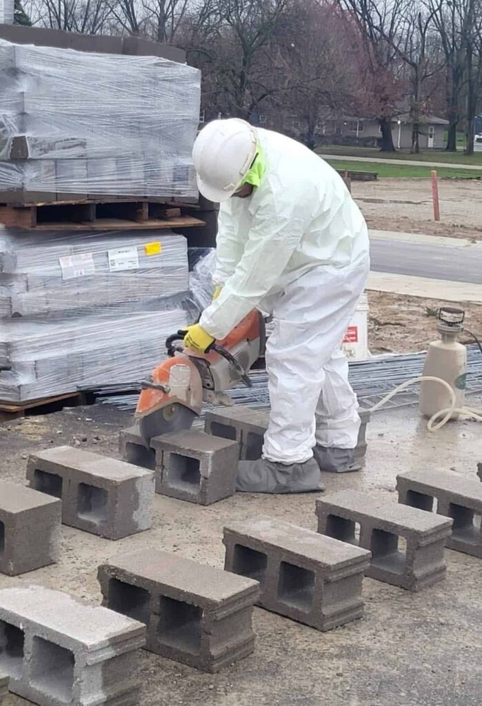 Construction worker cutting cinder block with saw