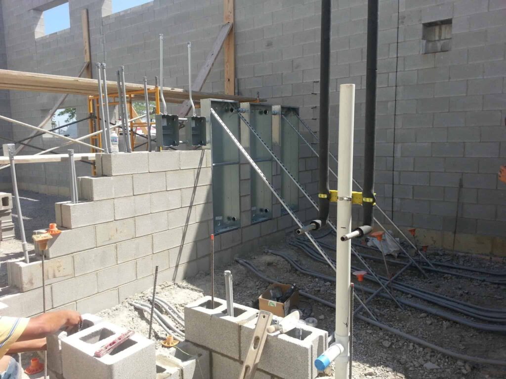 Electrical conduits and plumbing pipes being seamlessly installed within a wall by concrete block masonry Indianapolis contractors.