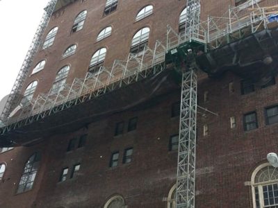 Industrial scaffolding set up for high-rise commercial masonry and facade restoration on a large brick building.